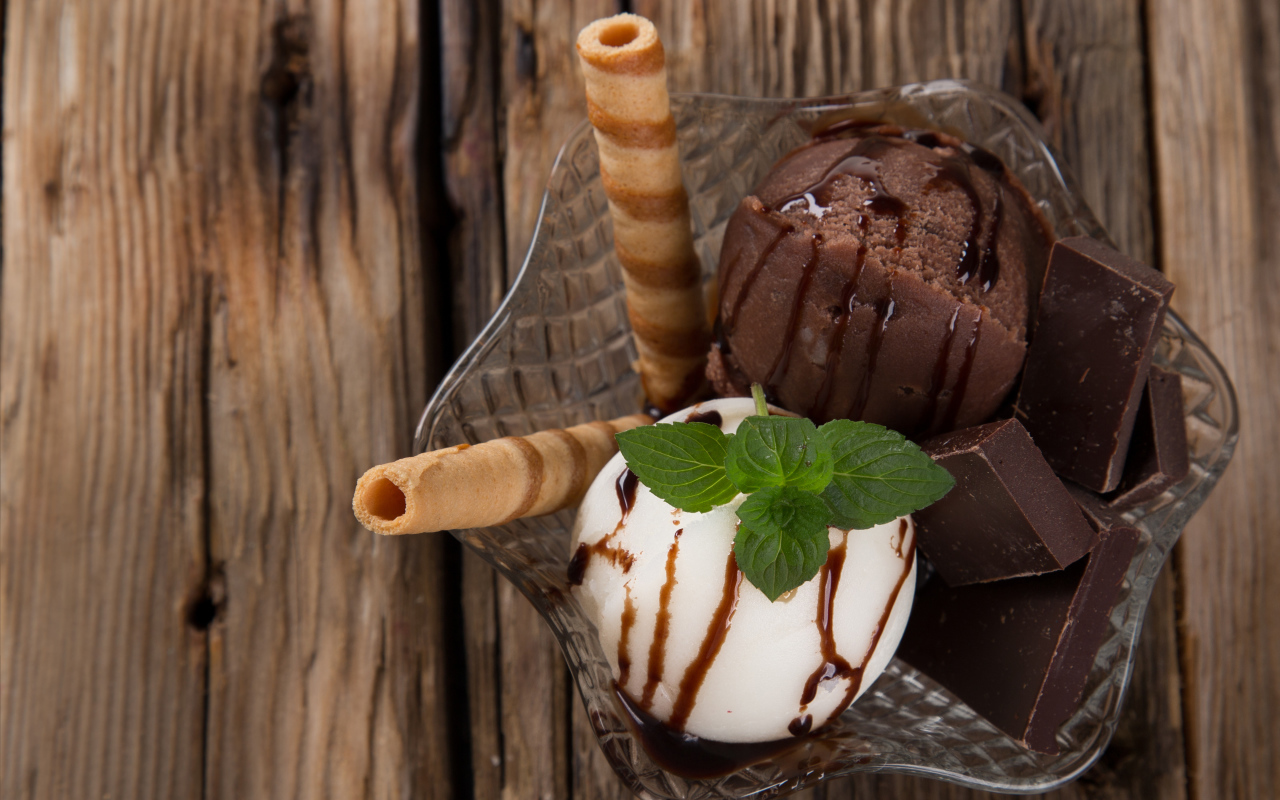 Шарик сливочного и шоколадного мороженого в пиале с трубочками