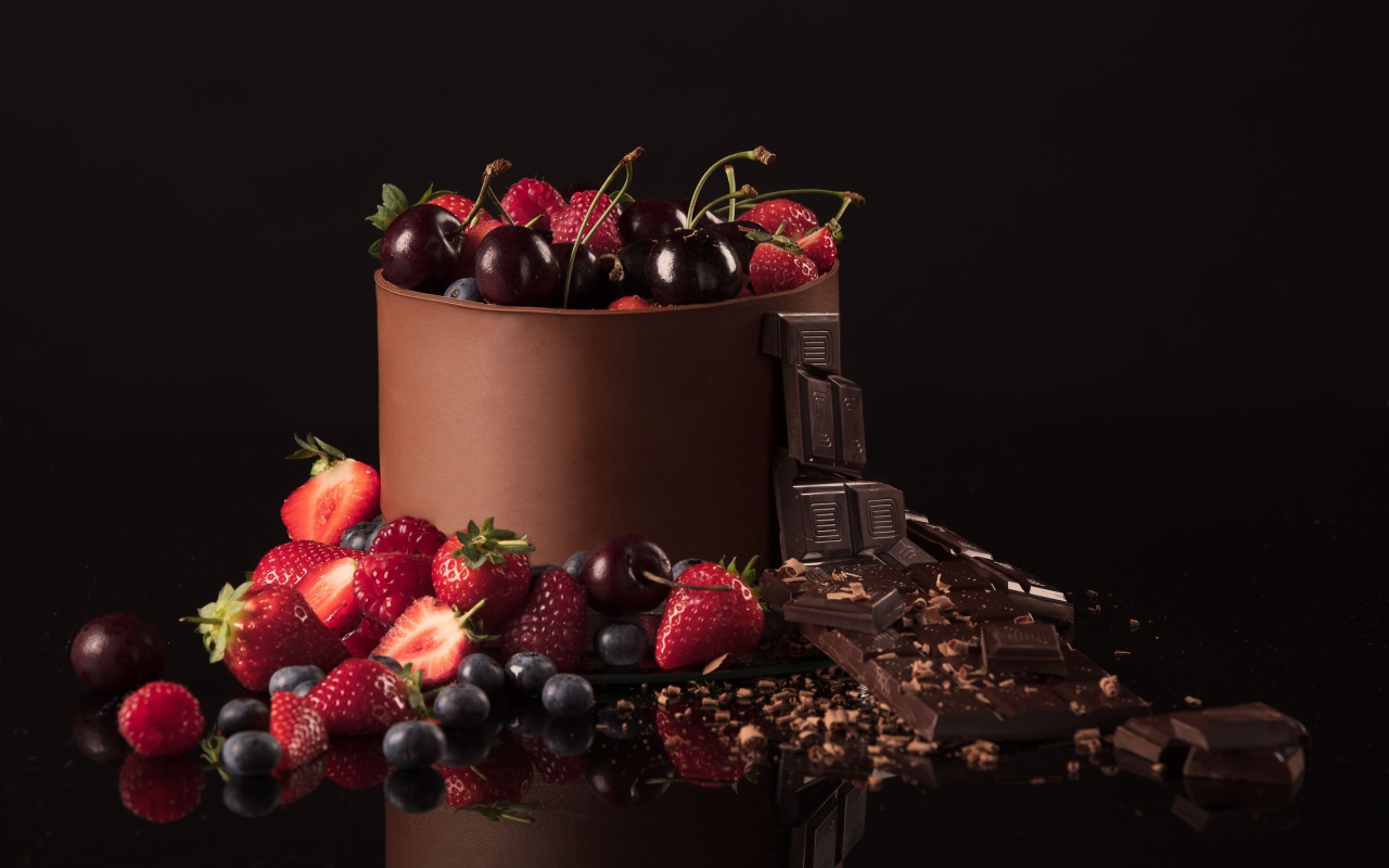 Черный шоколад с ягодами черники, малины, клубники и вишни на черном фоне
