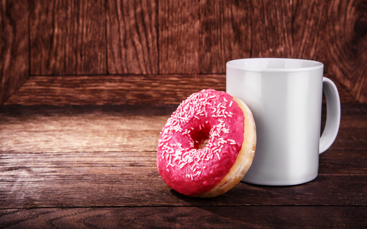 Пончик с белой кружкой на деревянном столе