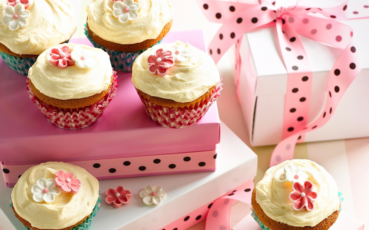 Праздничные кексы с кремом и подарочной коробкой на столе