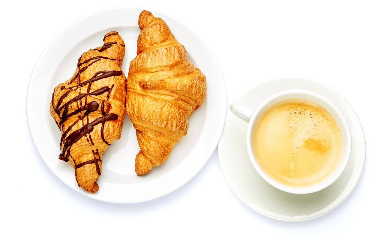 Два круассана с чашкой кофе на белом фоне