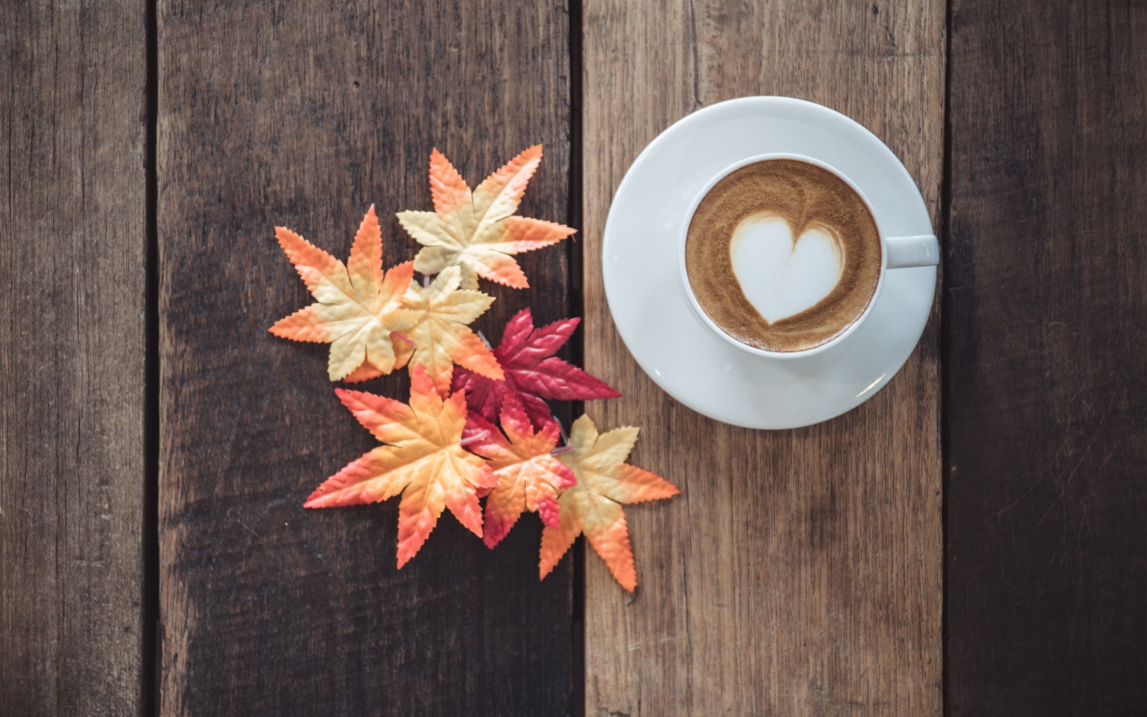 Чашка кофе на деревянном столе с желтыми листьями