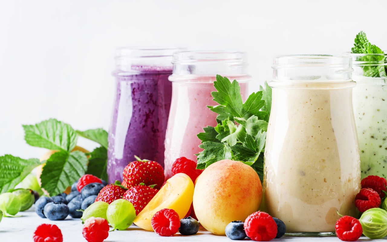 Ягодные смузи в бутылочках на столе с ягодами