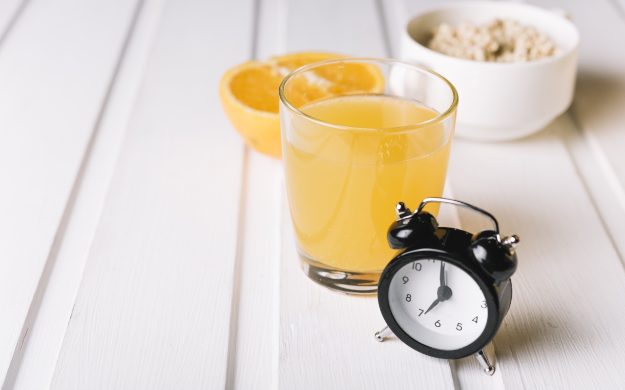 Черный будильник на столе со стаканом сока и хлопьями 