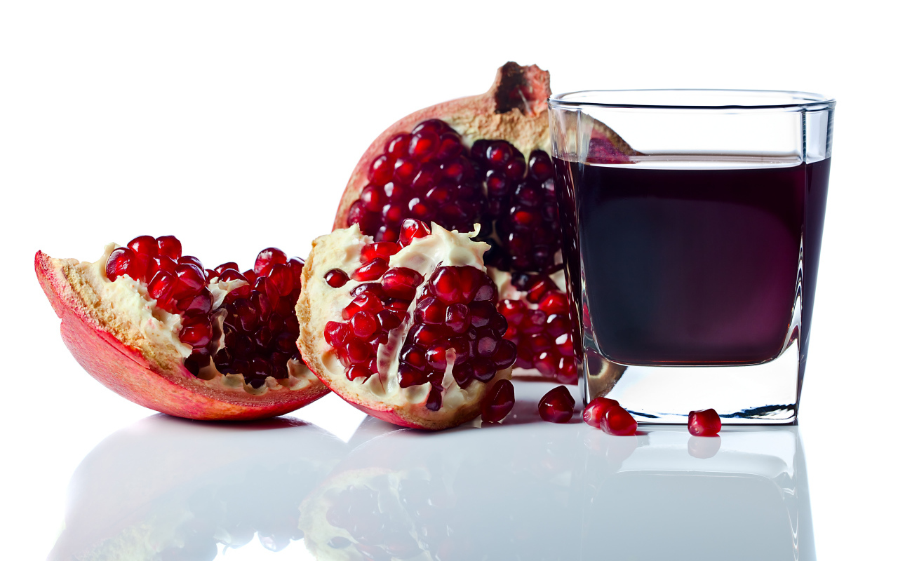 Гранатовый сок с плодом граната на белом фоне