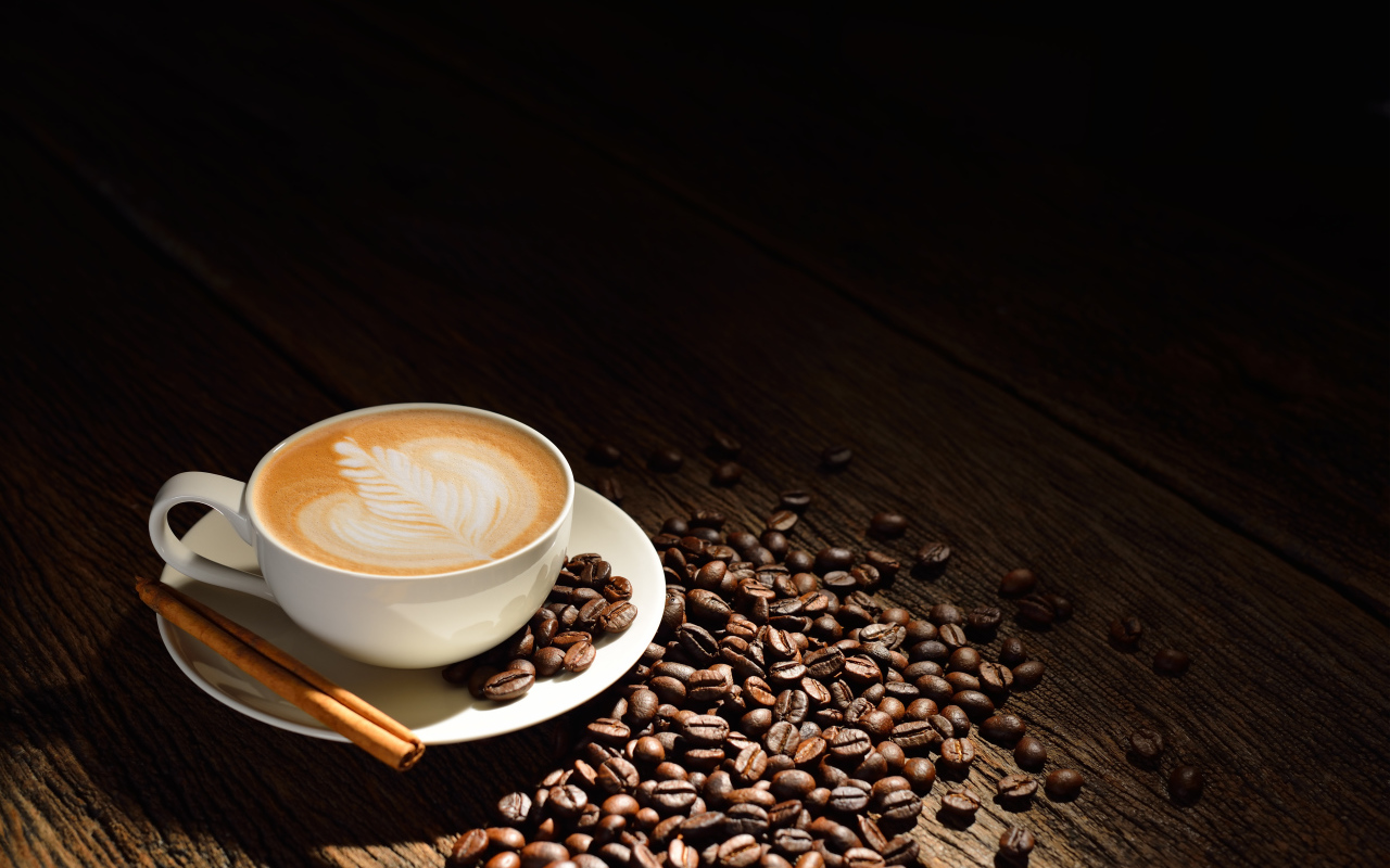 Белая чашка кофе с пенкой на столе с кофейными зернами и корицей