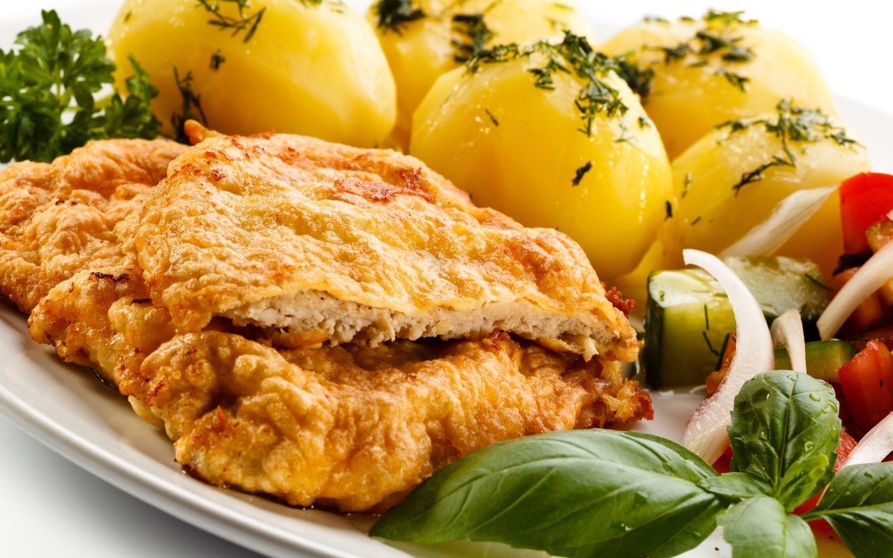 Отбивная на тарелке с вареным картофелем и салатом