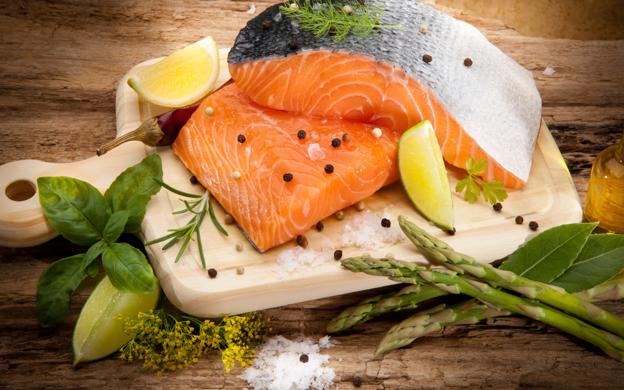 Филе красной рыбой на столе со спаржей и лаймом