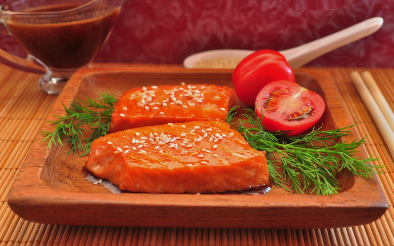 Red fish with sesame seeds on a plate with tomatoes and dill