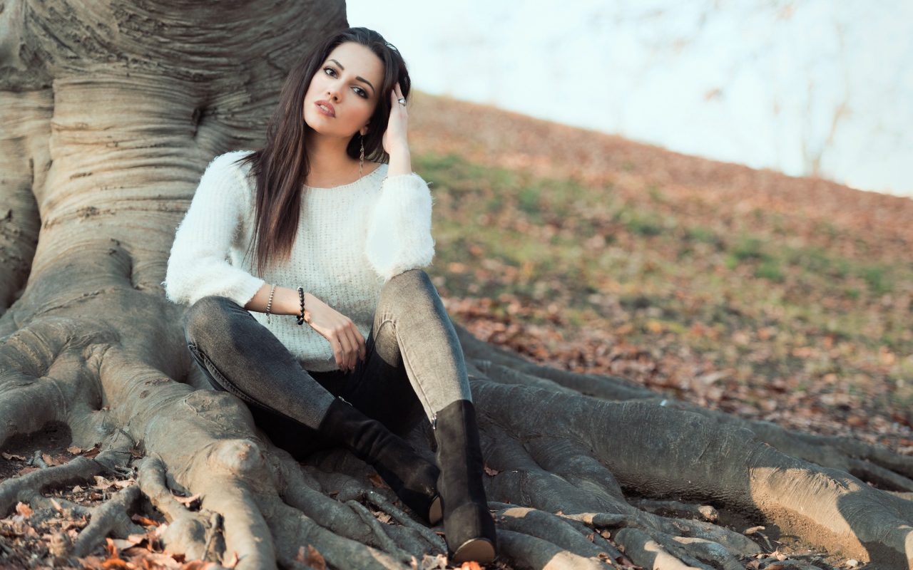 Красивая девушка сидит у дерева