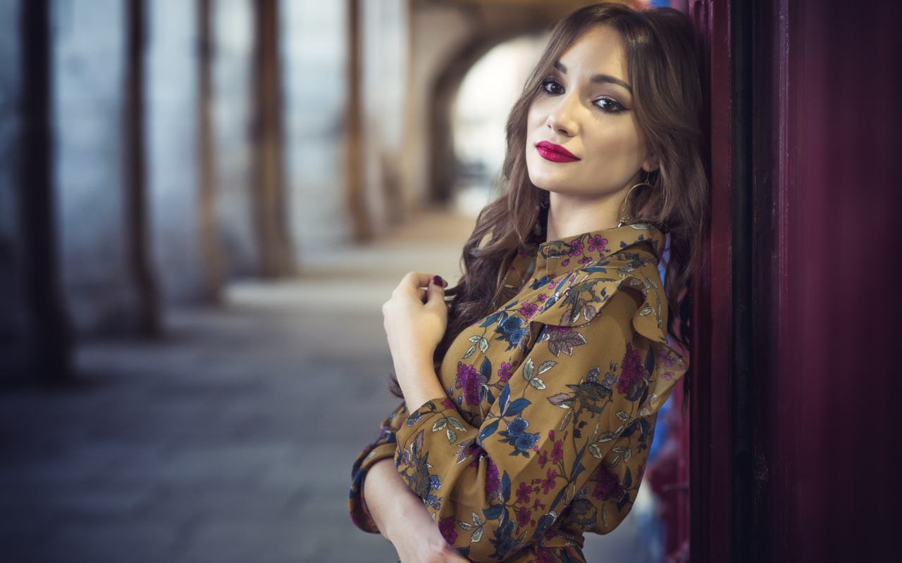 Девушка шатенка в красивом платье у стены