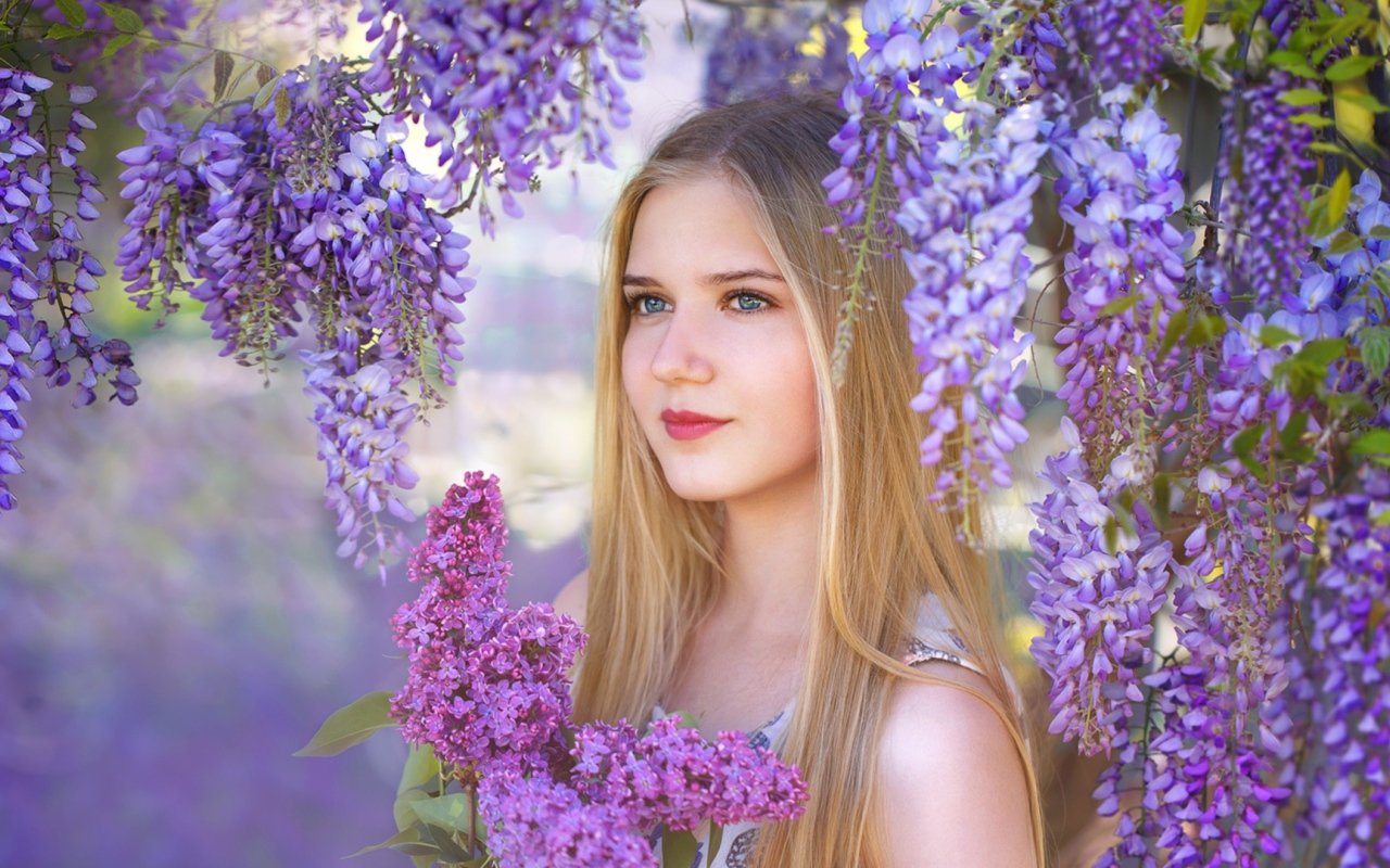 Красивая блондинка с букетом сирени на фоне цветов глицинии