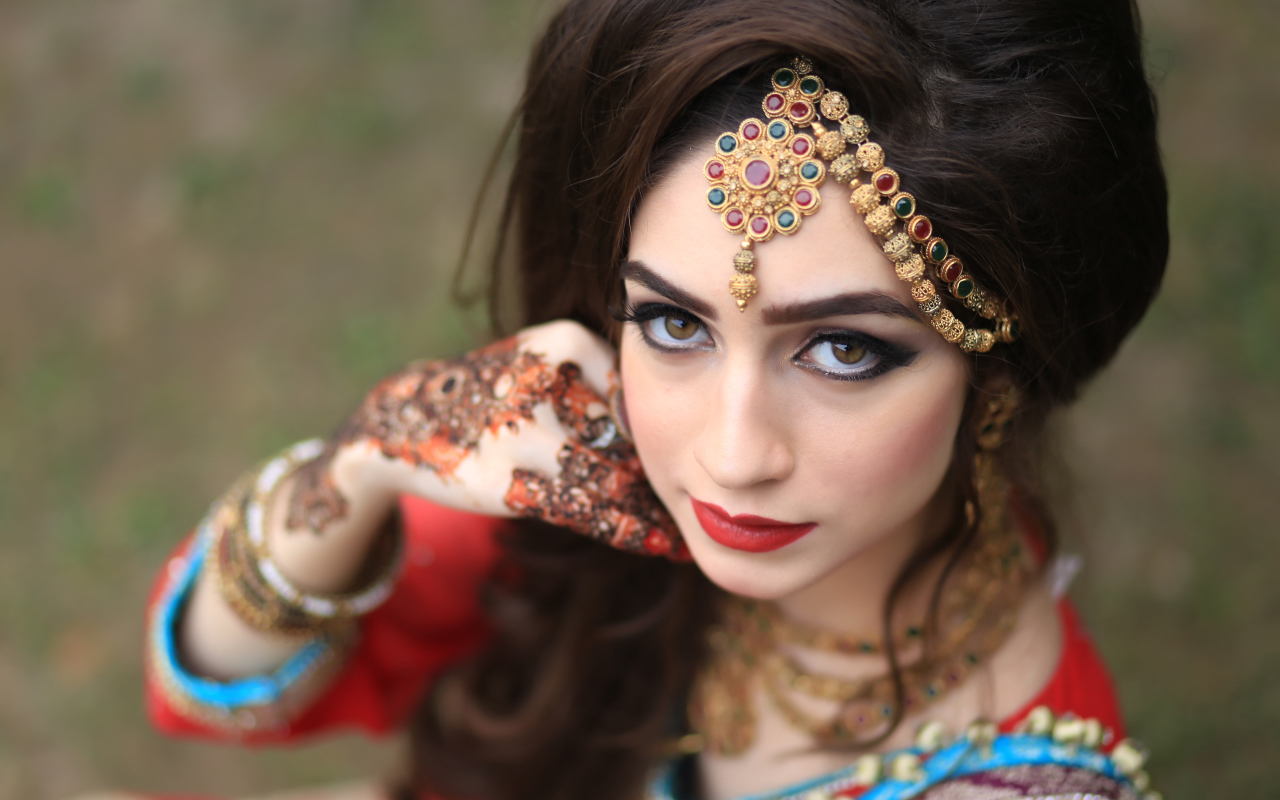 Красивая кареглазая девушка в индийском костюме с рисунками на руках 