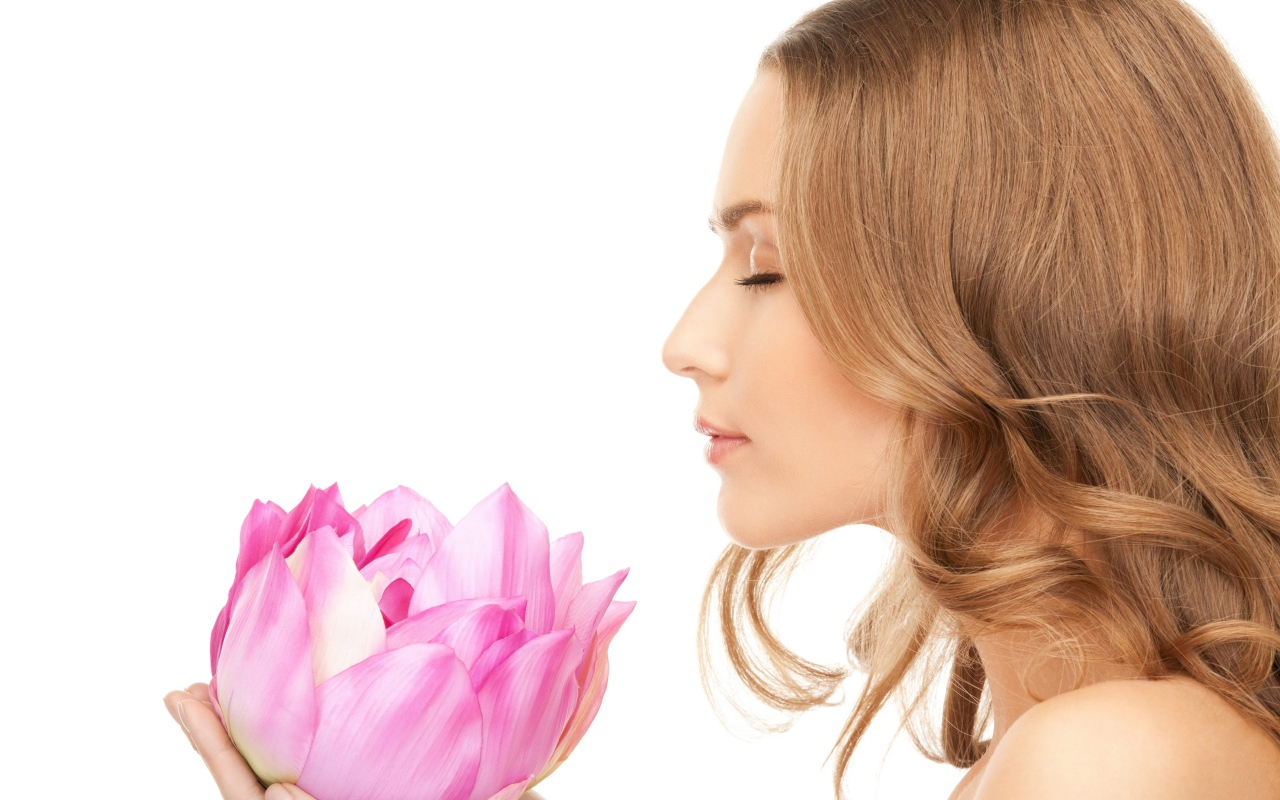 Красивая девушка шатенка наслаждается ароматом лотоса 