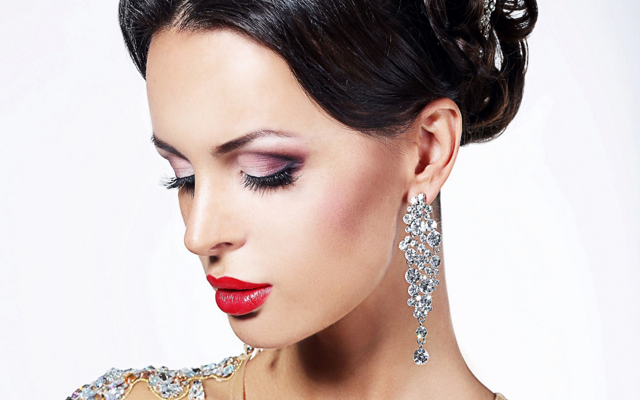 Красивая брюнетка в дорогих украшениях на белом фоне