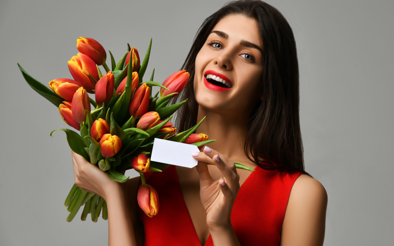 Красивая брюнетка с букетом тюльпанов на сером фоне