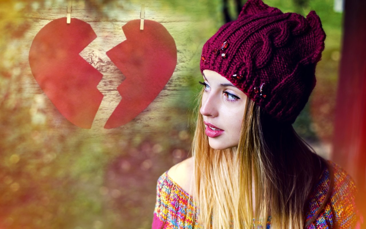 Красивая девушка в вязаной шапке на фоне разбитого сердца