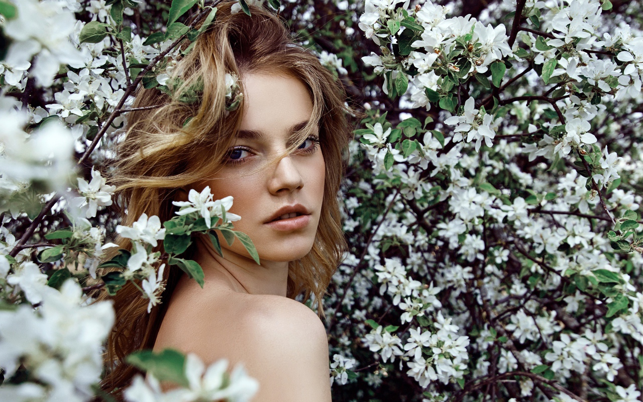 Красивая девушка в ветках цветущей яблони 