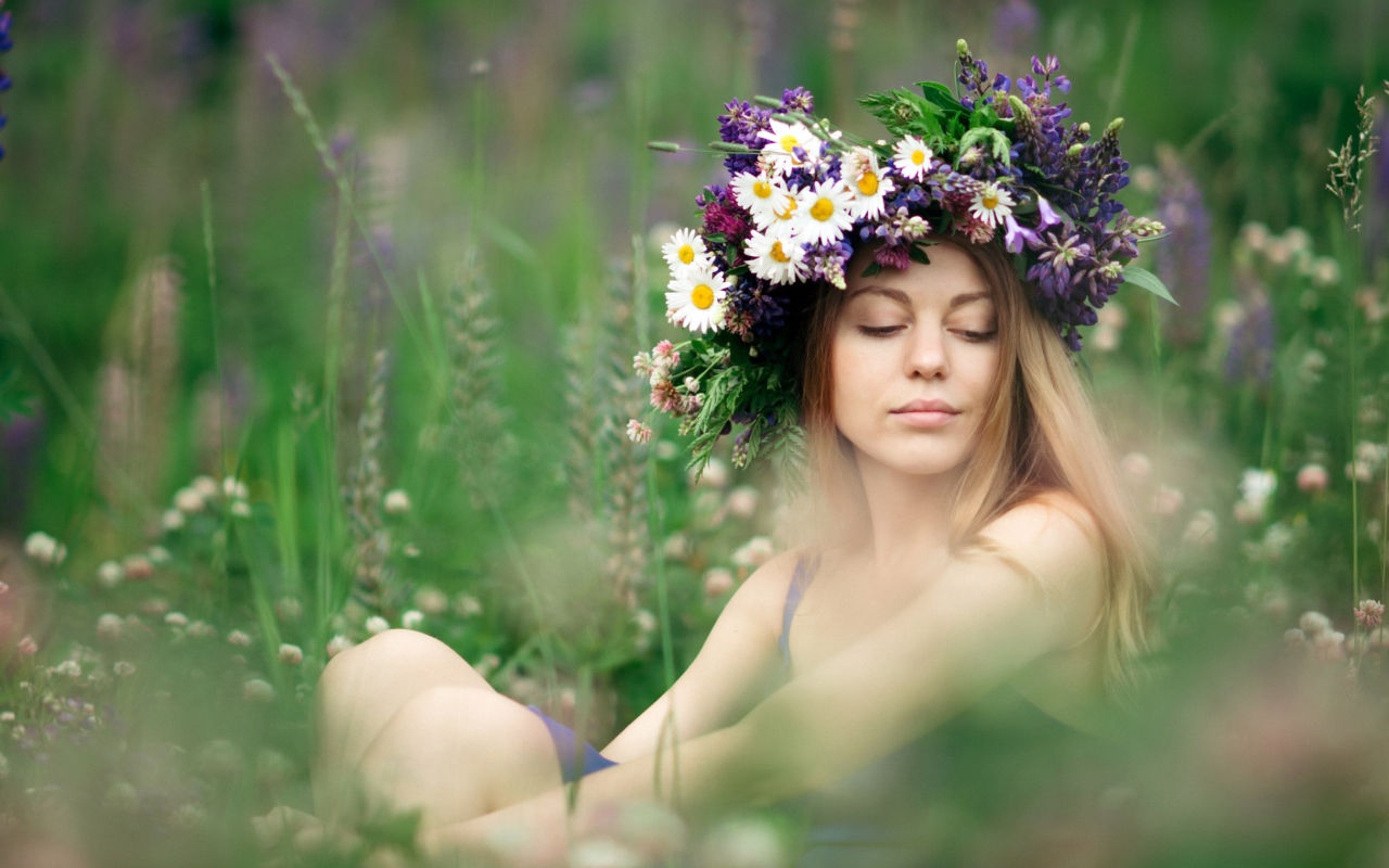 Красивая девушка с венком из полевых цветов на голове летом 