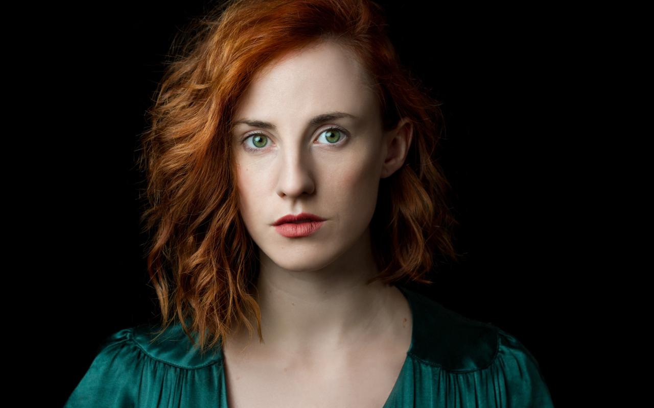 Красивая зеленоглазая рыжеволосая девушка на черном фоне 