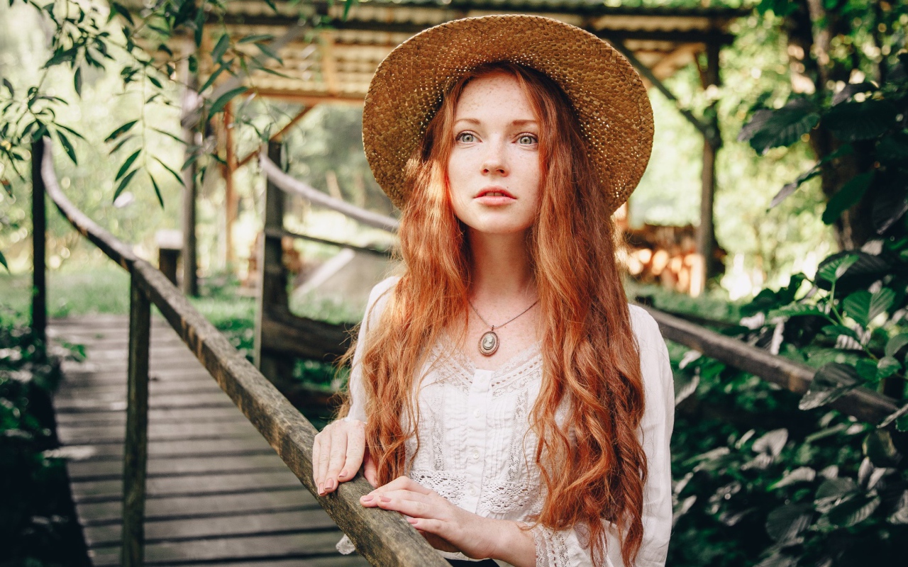 Красивая рыжеволосая девушка в соломенной шляпе