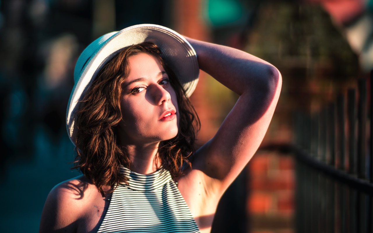 Красивая молодая девушка в белой шляпе в свете солнца