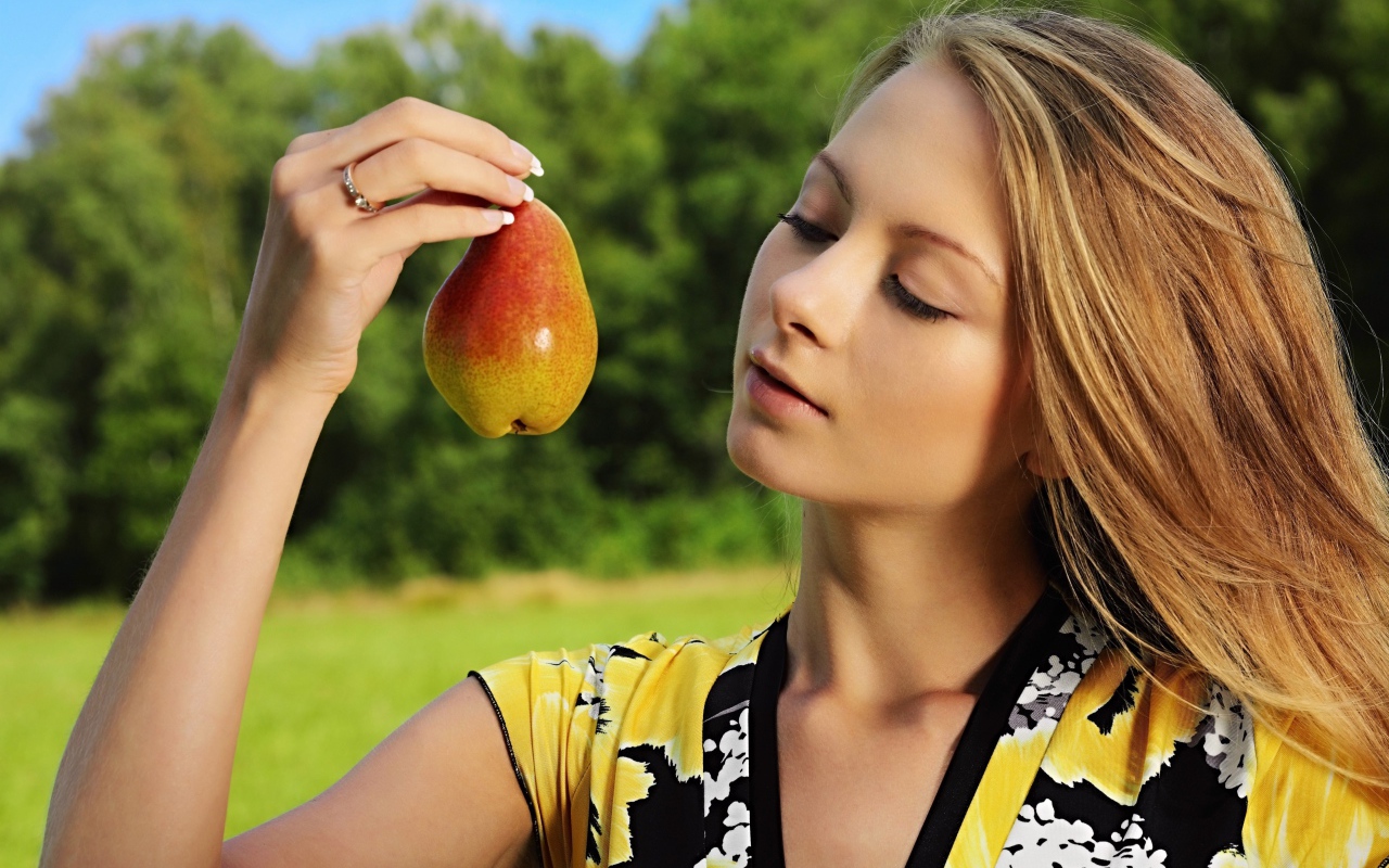 Красивая молодая девушка с грушей в руках