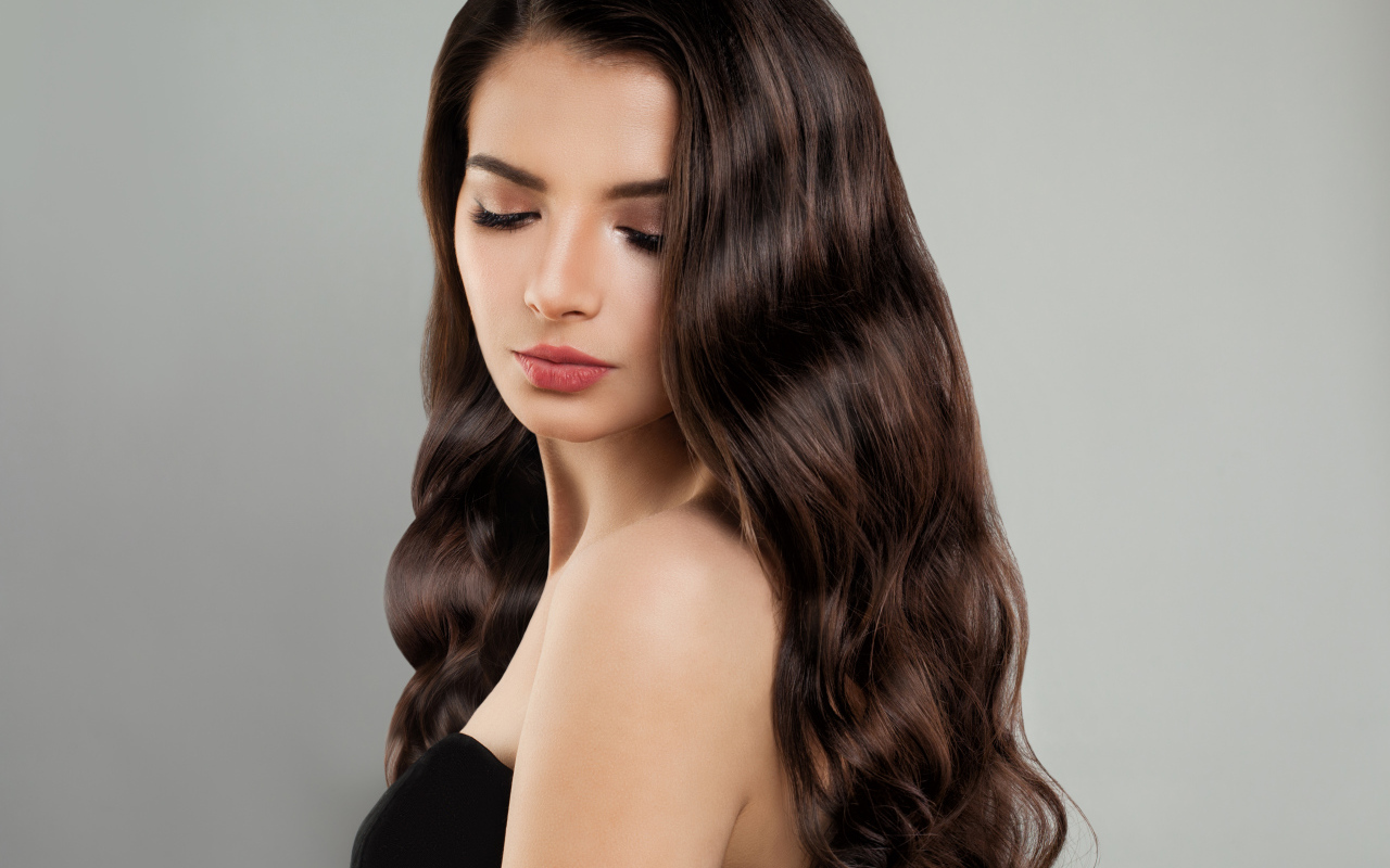 Красивая молодая длинноволосая девушка брюнетка на сером фоне