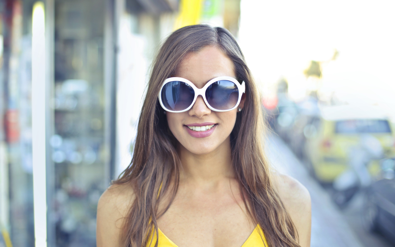 Улыбающаяся молодая девушка в солнечных очках 