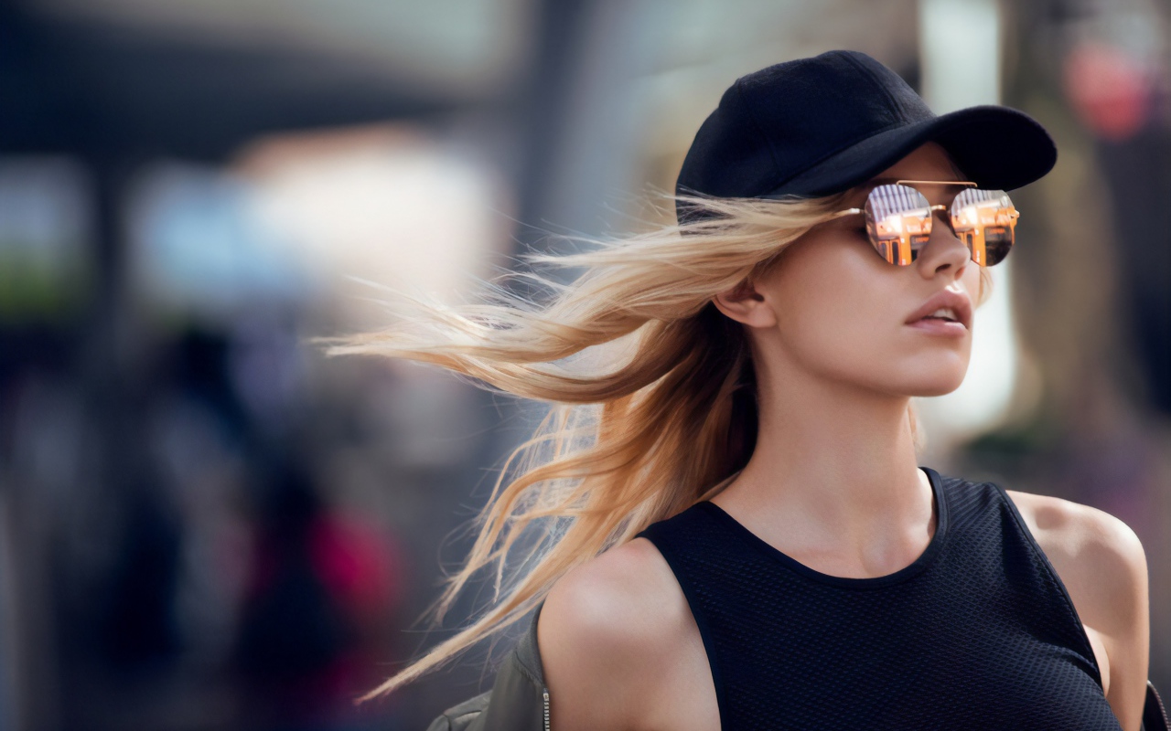 Молодая блондинка в солнечных очках и черной кепке 