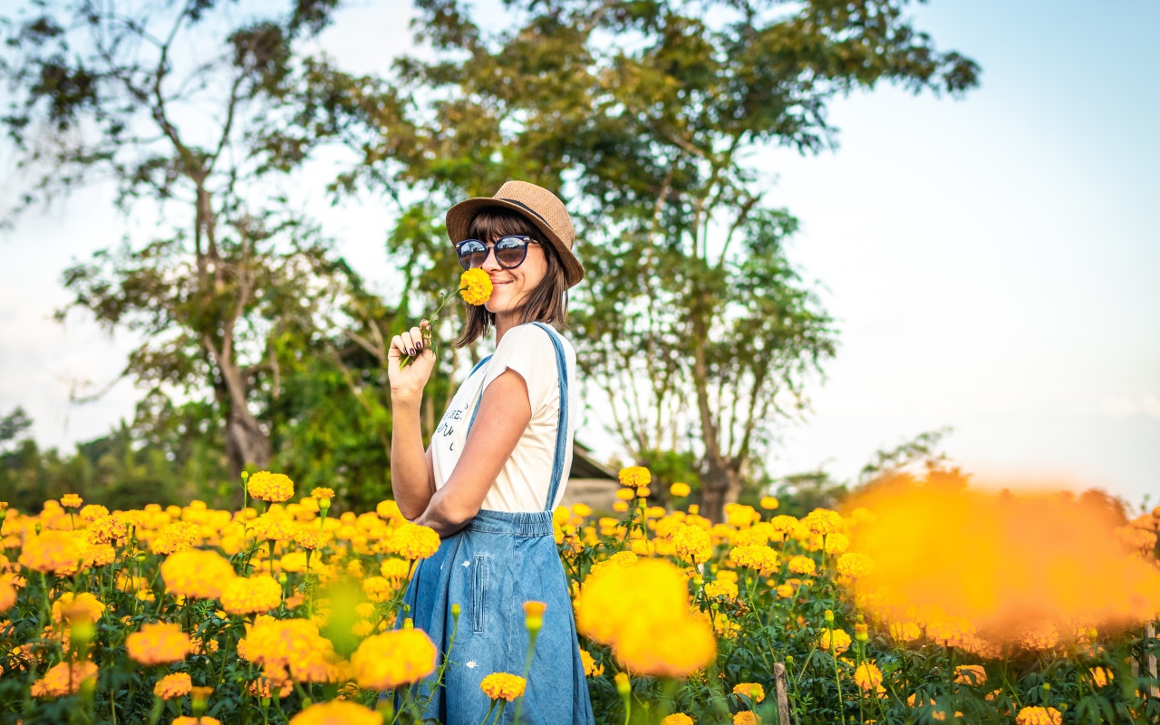 Молодая девушка в солнечных очках в желтых цветах 