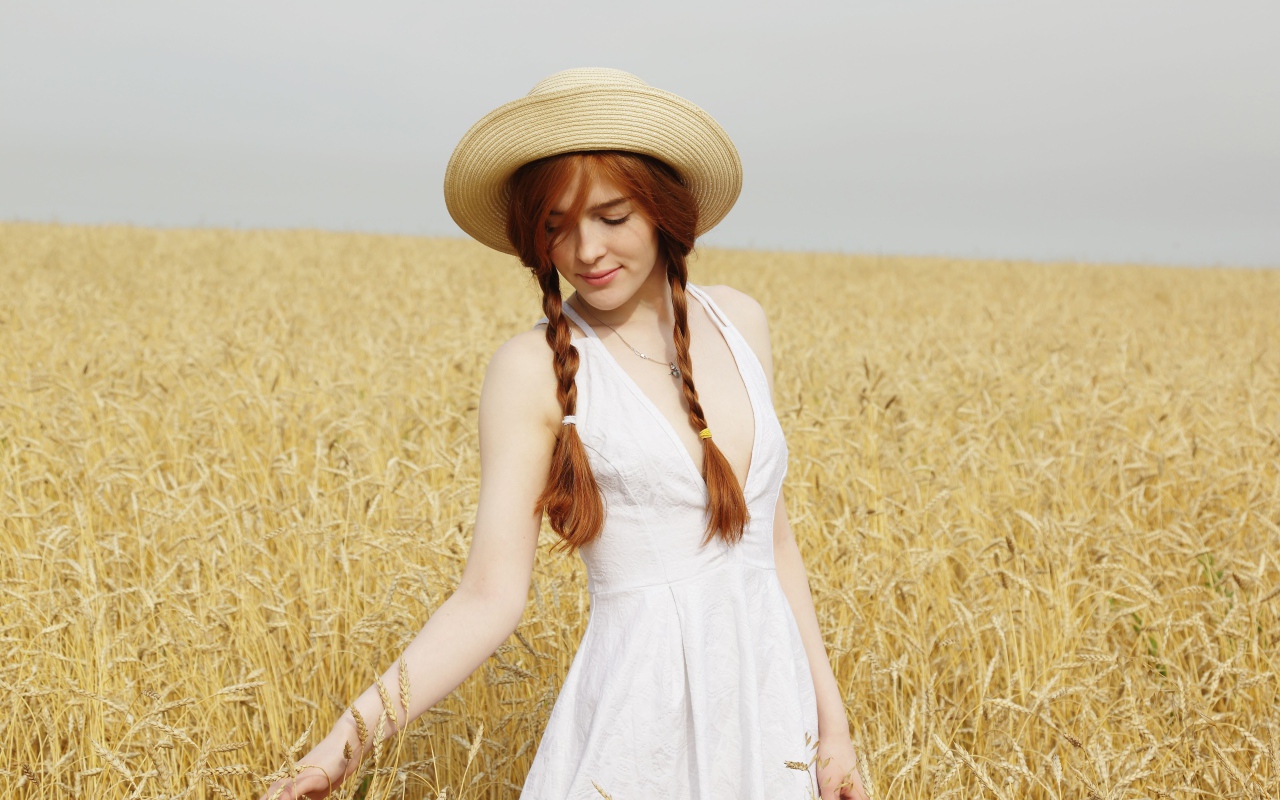 Молодая девушка в белом платье на поле с пшеницей