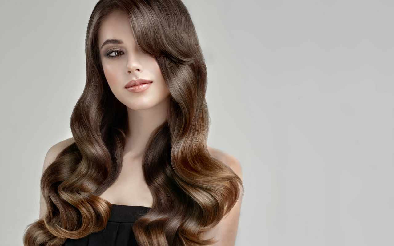 Молодая девушка с красивыми длинными волосами на сером фоне