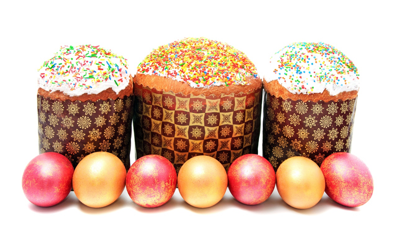 Три пасхальных кулича с крашеными яйцами на белом фоне на праздник Пасха