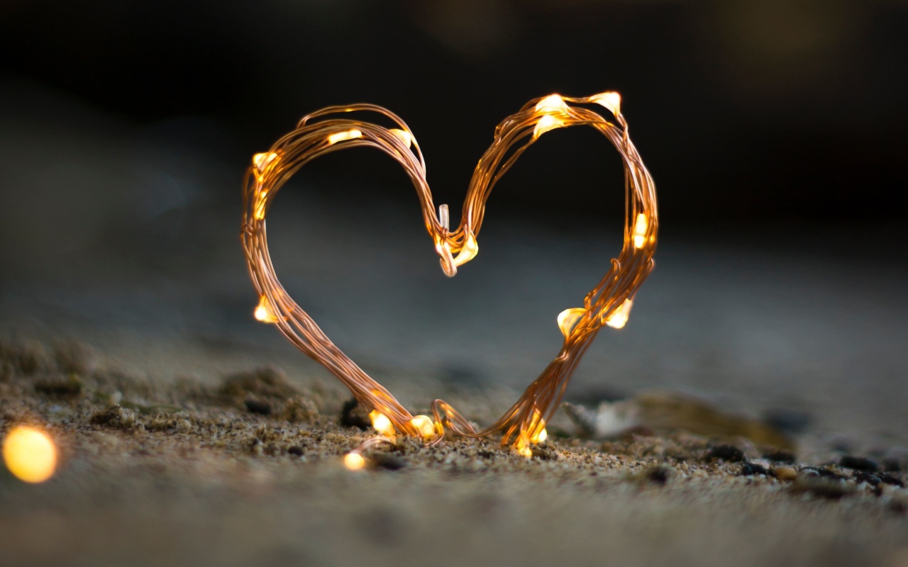 Сердце из гирлянды на песке