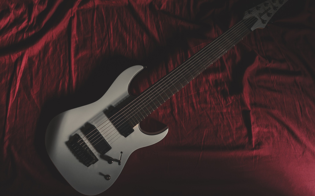 Гитара лежит на красном покрывале