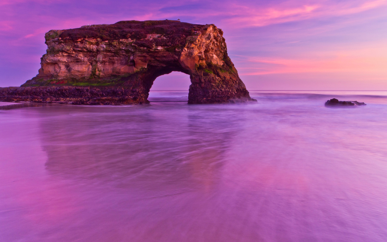 Гора с аркой в океане на фоне красивого неба