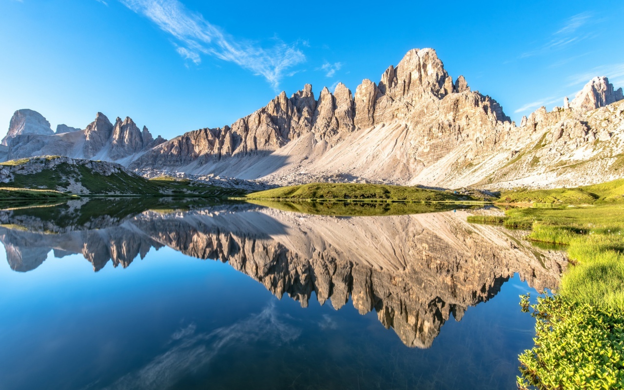 Горы и голубое небо отражаются в чистой воде 