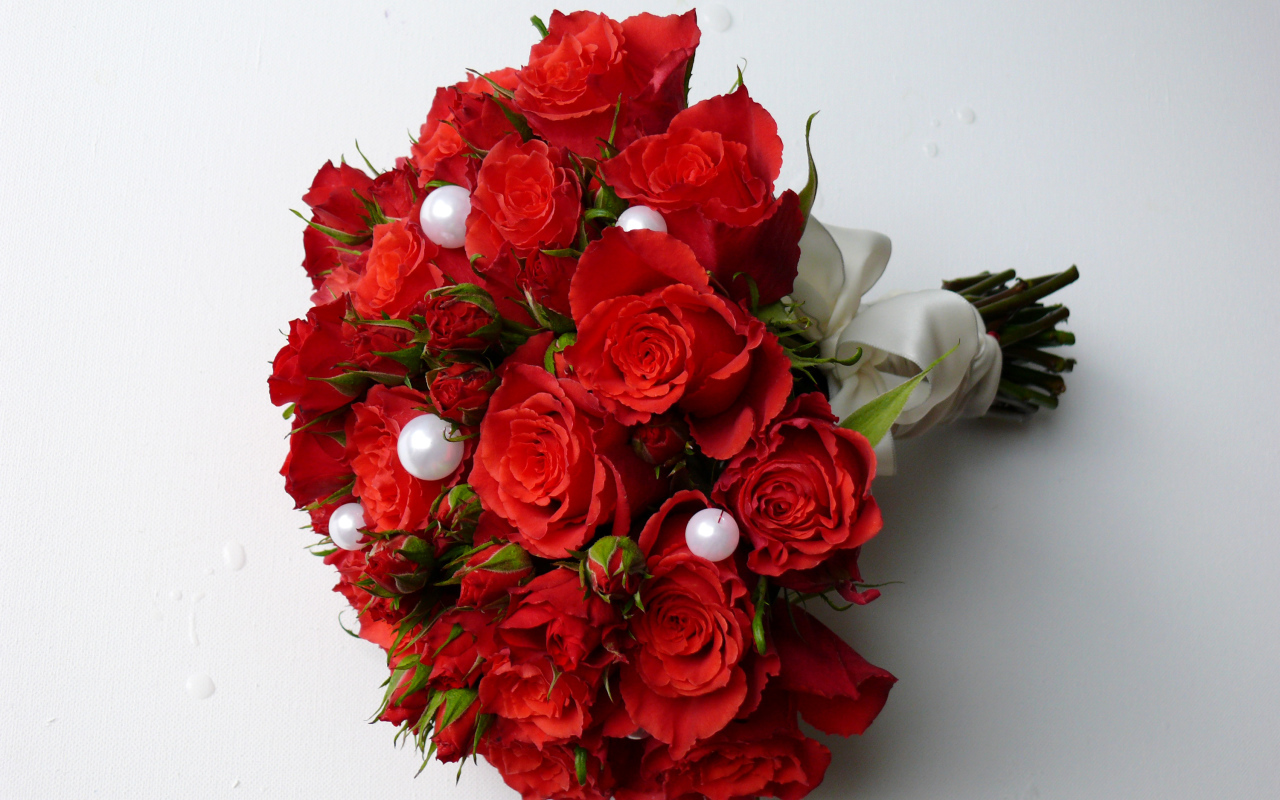Красивый букет красных роз с жемчужными бусинами на сером фоне