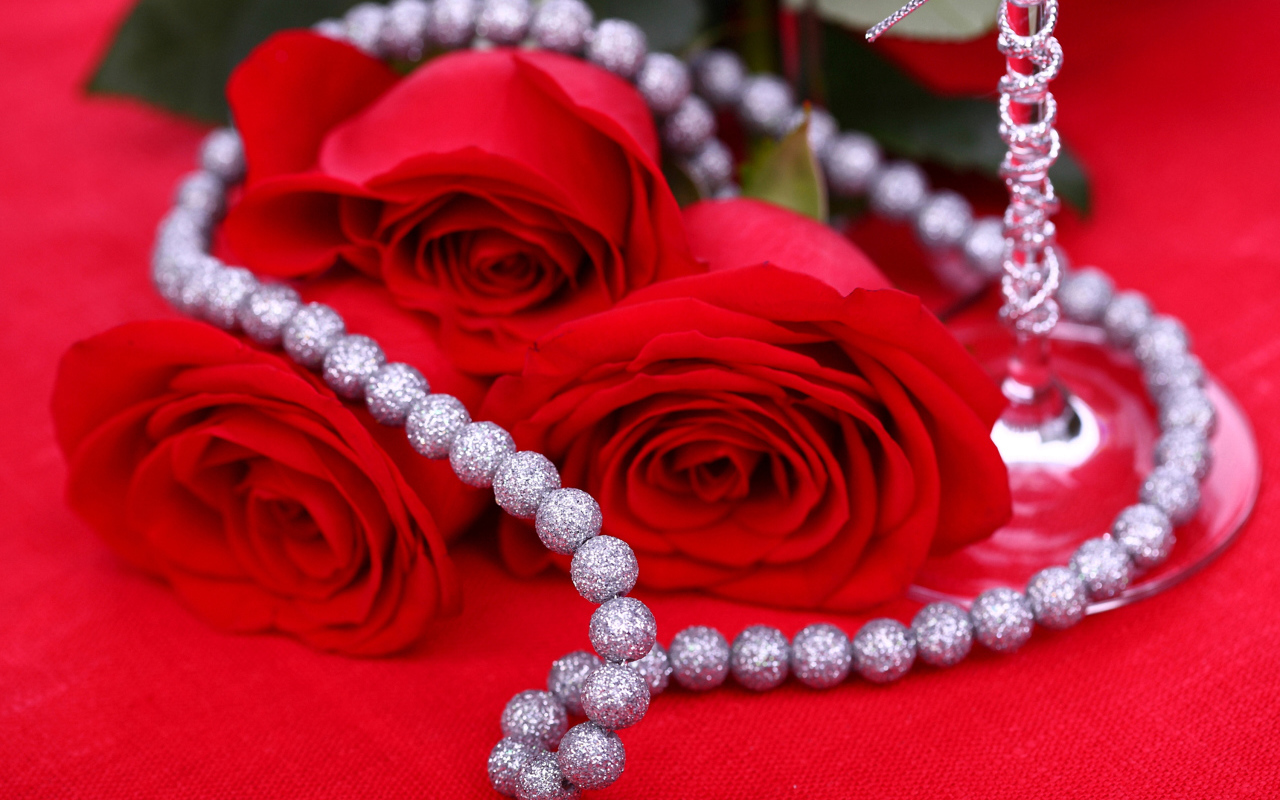 Три красные розы с украшением на красном фоне