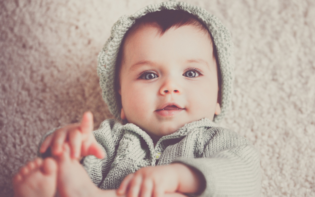 Маленький милый голубоглазый малыш в вязаном костюме