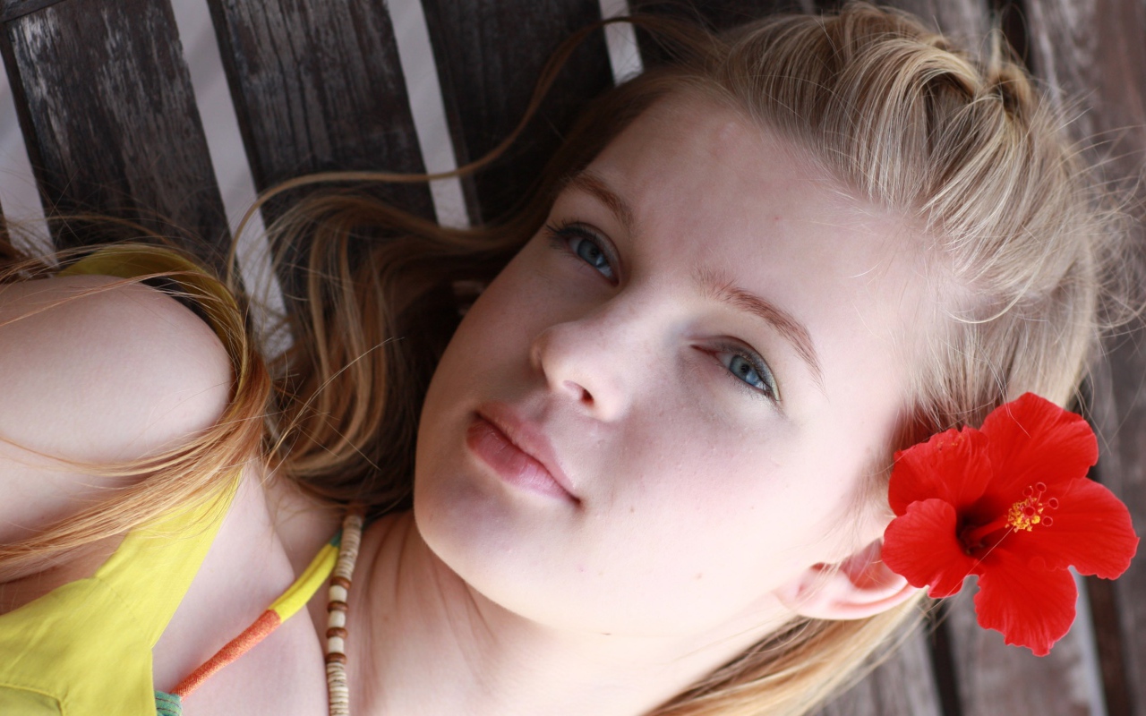 Девочка с красным цветком гибискуса в волосах