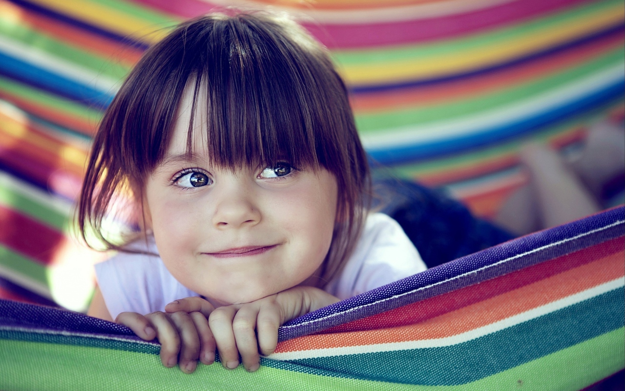 Маленькая кареглазая девочка лежит в гамаке