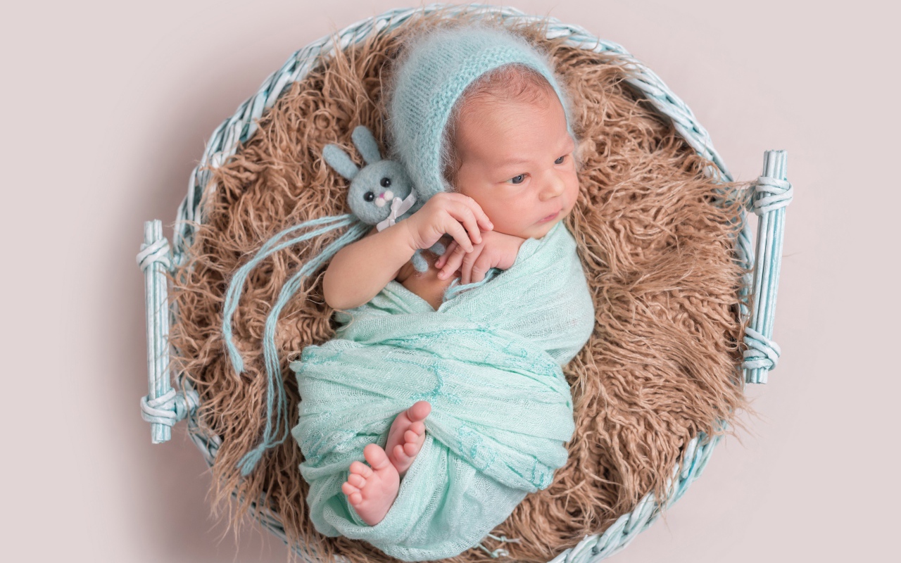 Маленький ребенок в корзине на сером фоне