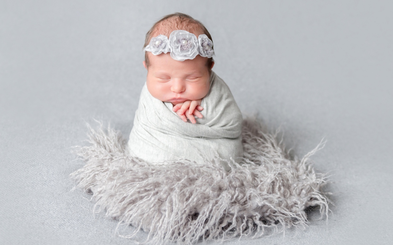 Маленький спящий младенец на сером фоне