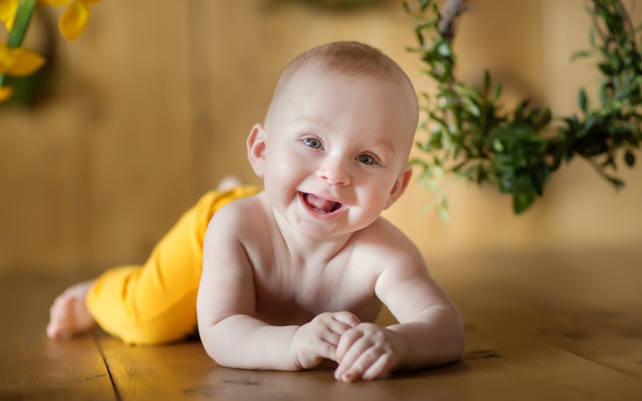 Улыбающийся малыш лежит на деревянном полу