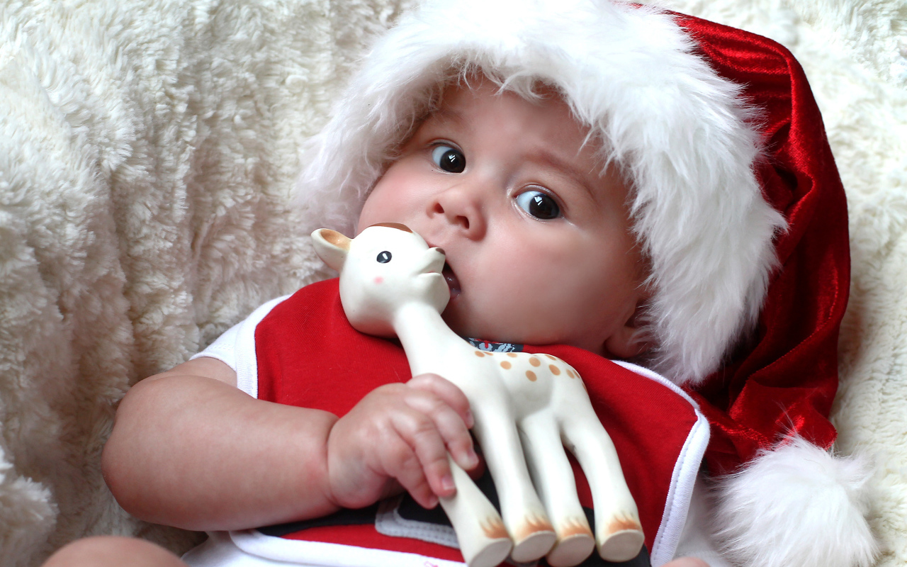 Маленький ребенок в новогодней шапке с игрушкой в руке