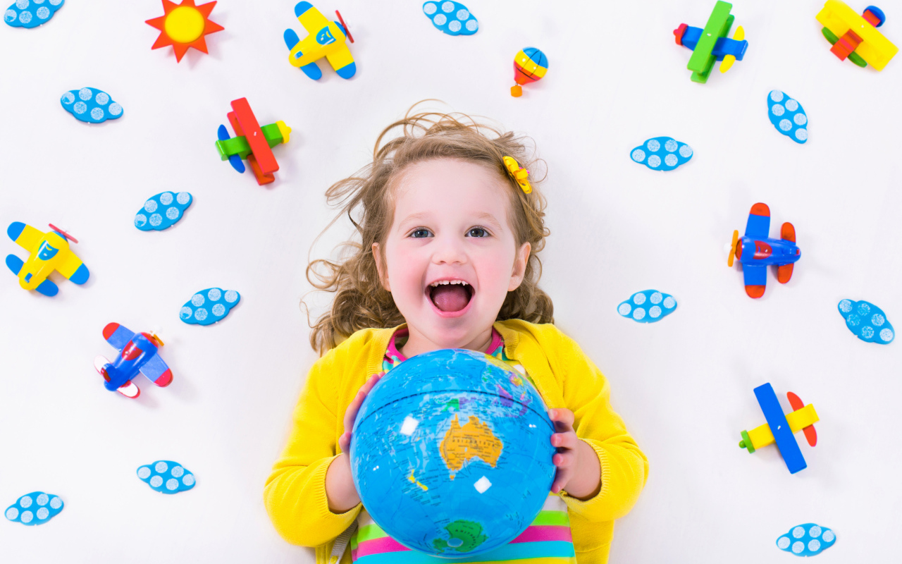 Маленькая веселая девочка с глобусом в руках 