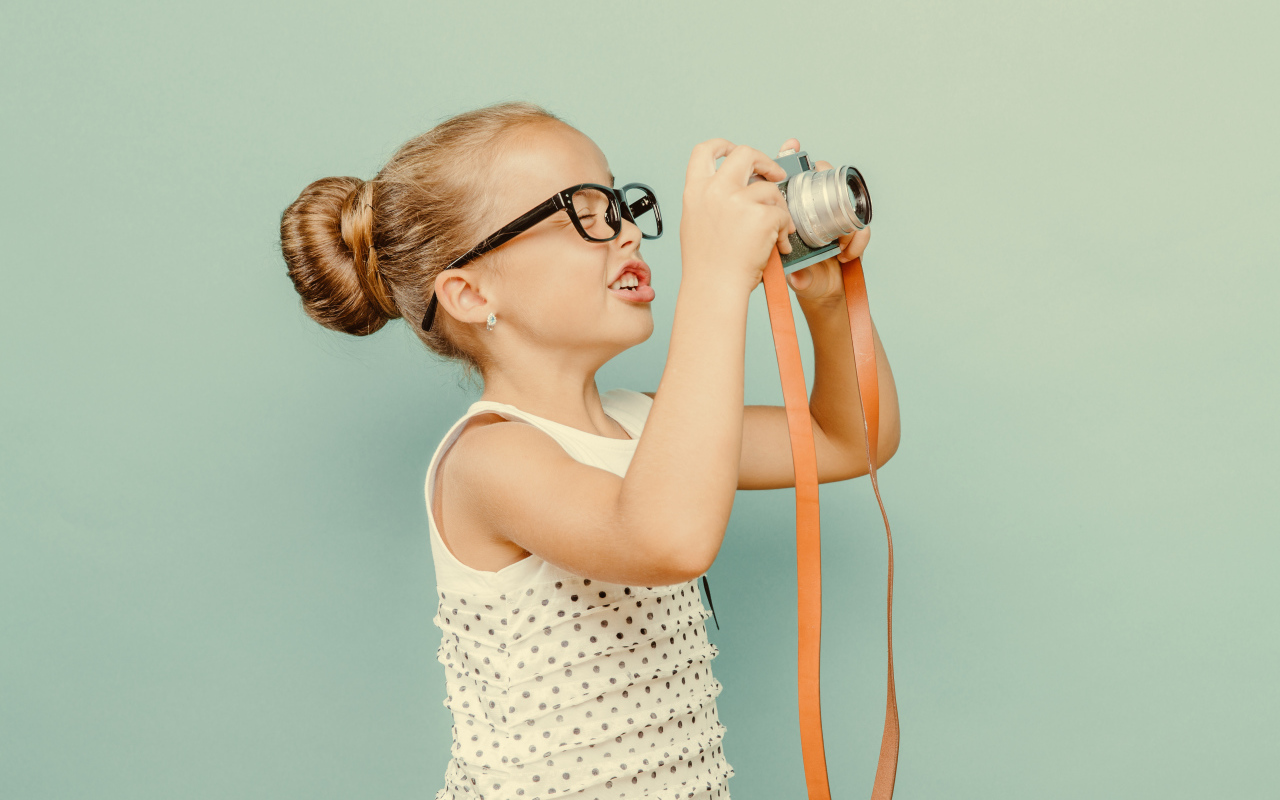 Маленькая девочка в очках с фотоаппаратом