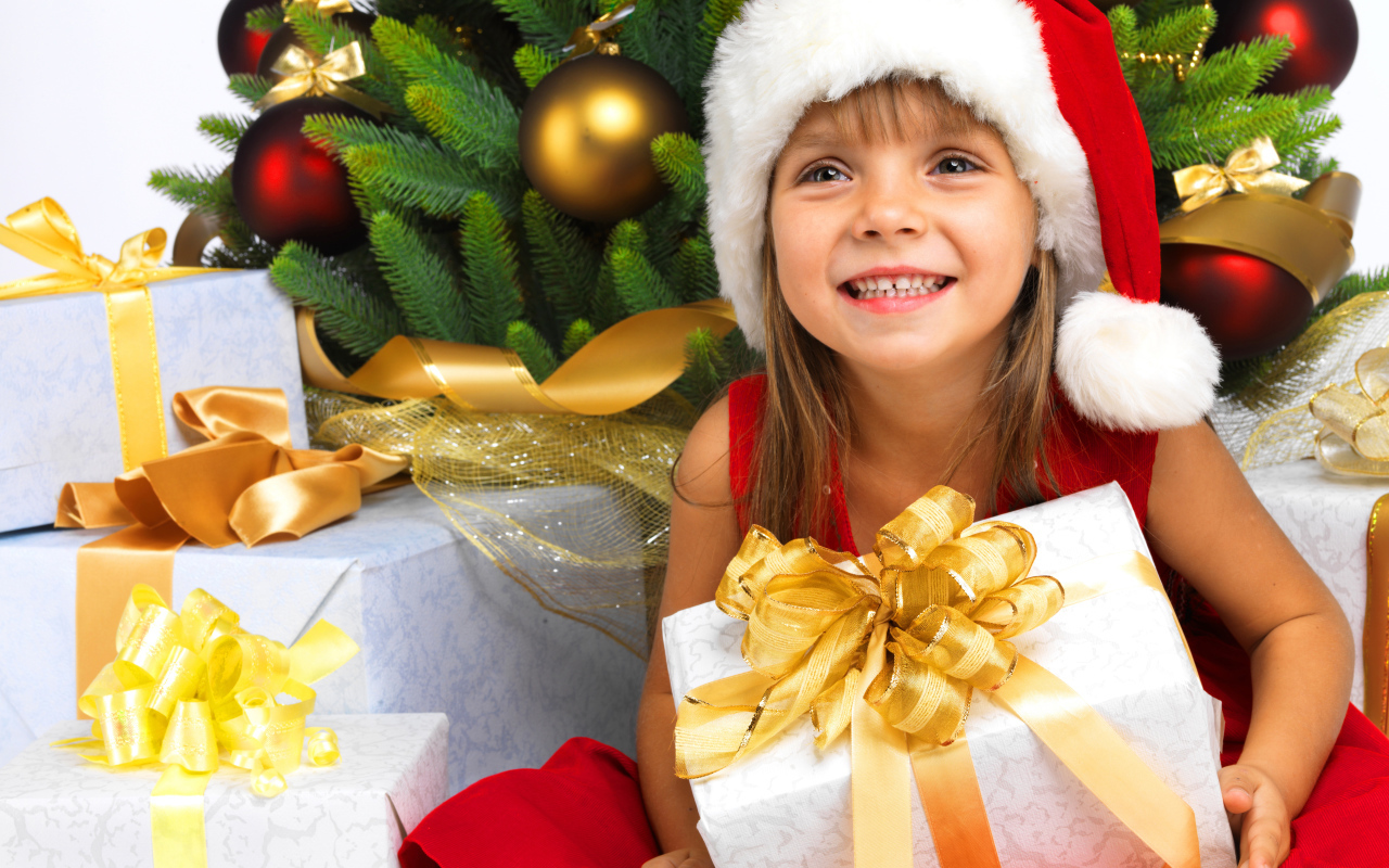 Улыбающаяся девочка в новогоднем костюме с подарками под елкой
